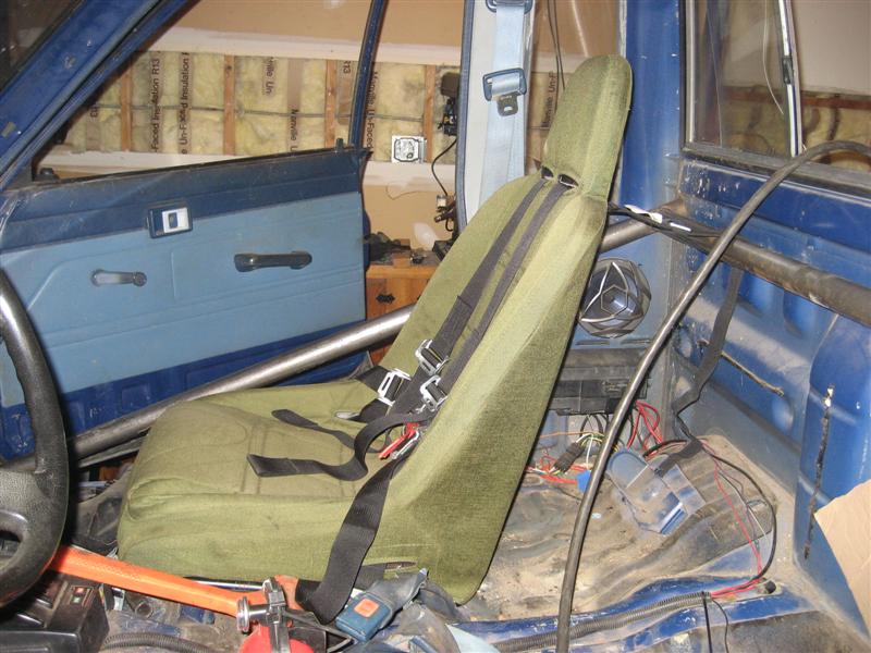 Shoulder belts mounted to harness bar on interior of cab.