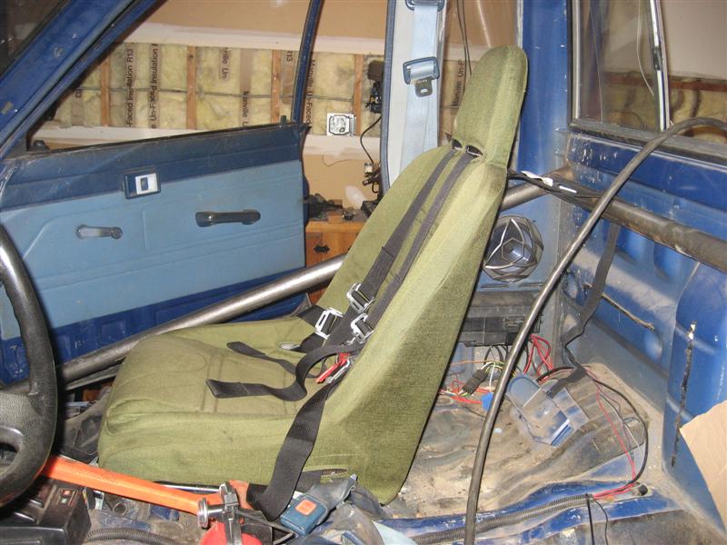 Shoulder belts mounted to harness bar on interior of cab.